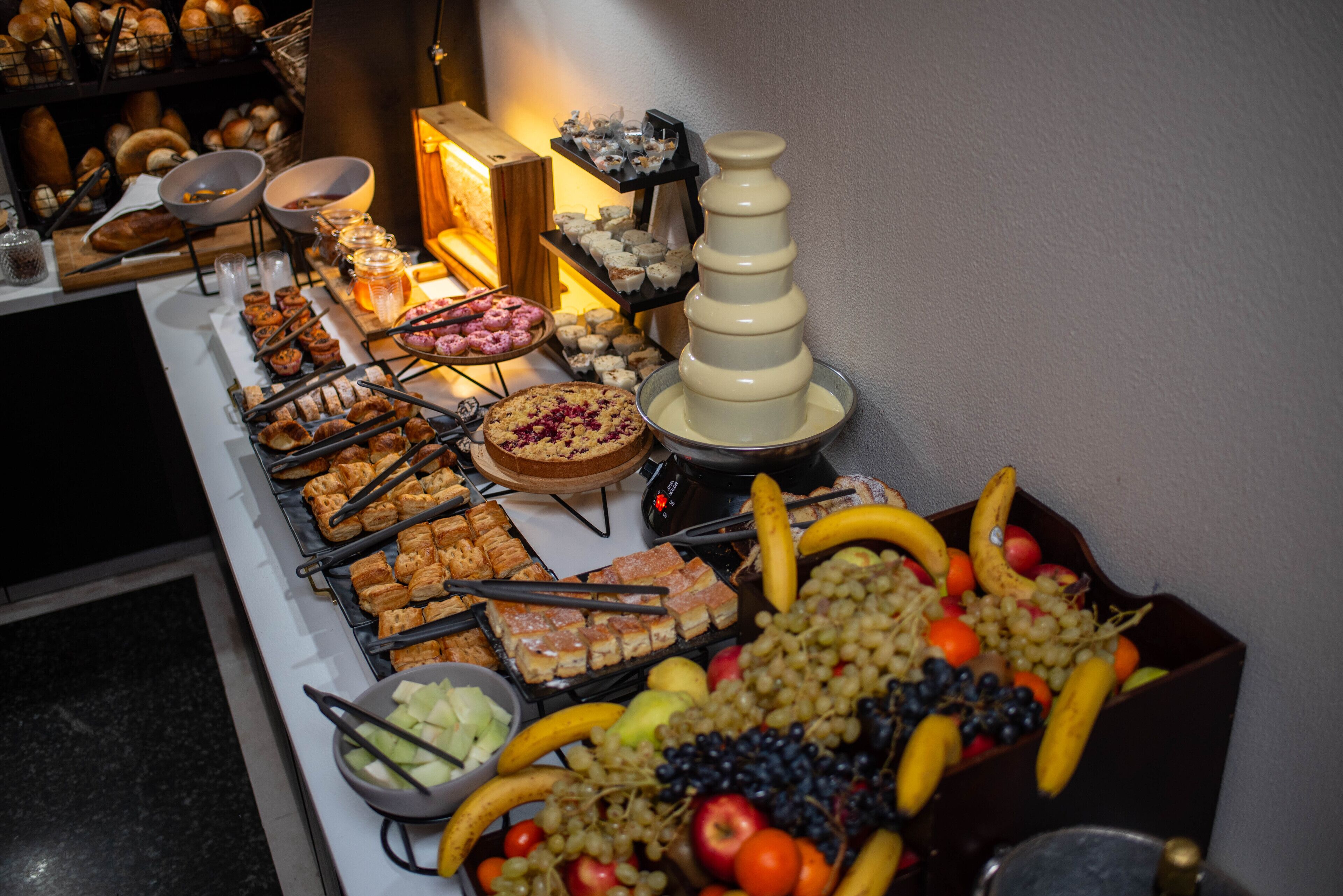 A buffet with various food items including pastries, fruits, and desserts.