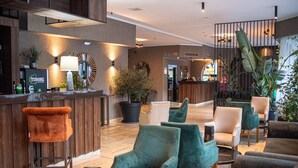 A lobby with a reception desk, bar stools, and seating areas with chairs and sofas. - Hotel Carpathia (Sinaia)