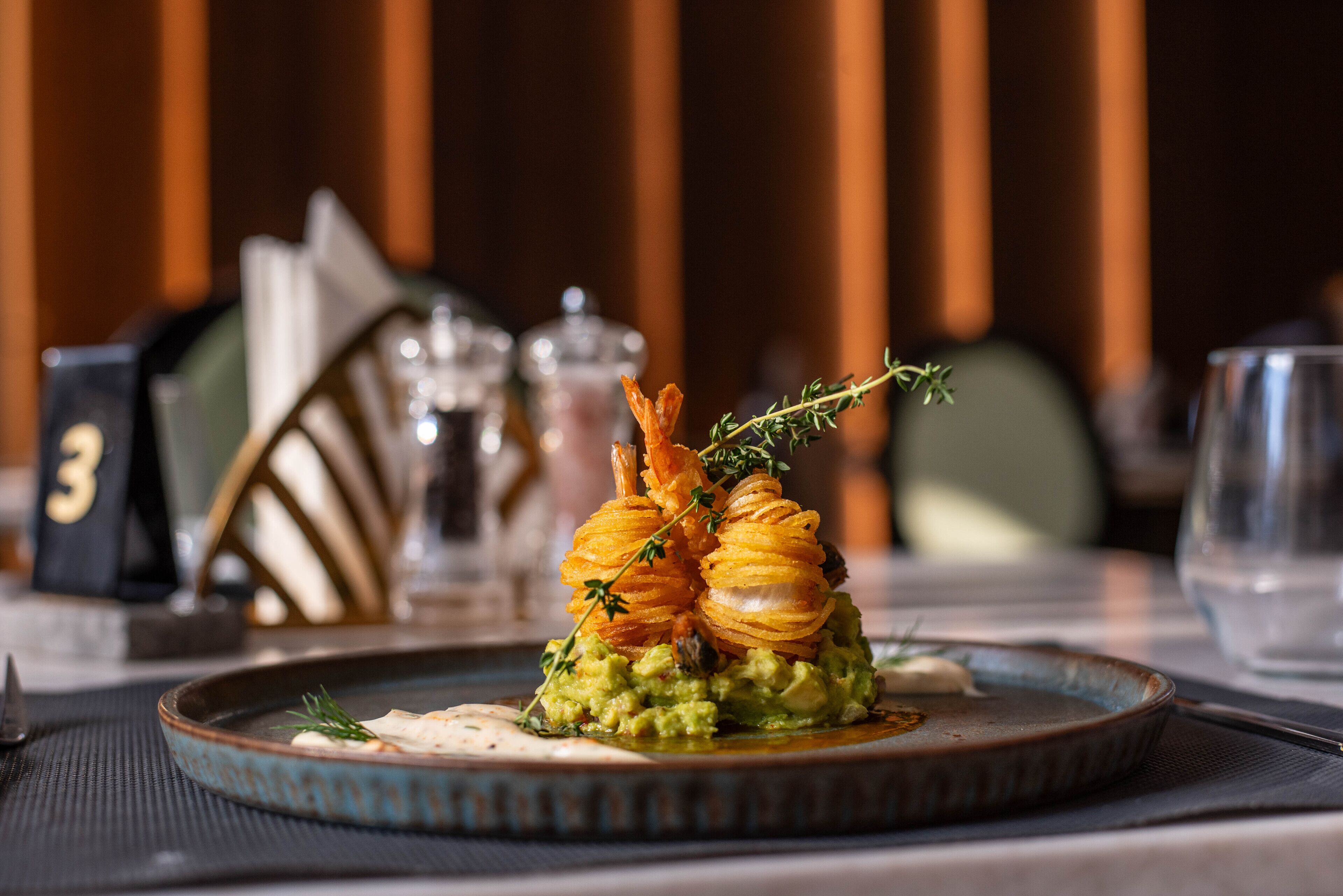 A plate of food with a decorative arrangement of what appears to be fried items and herbs, set on a table with a placemat.