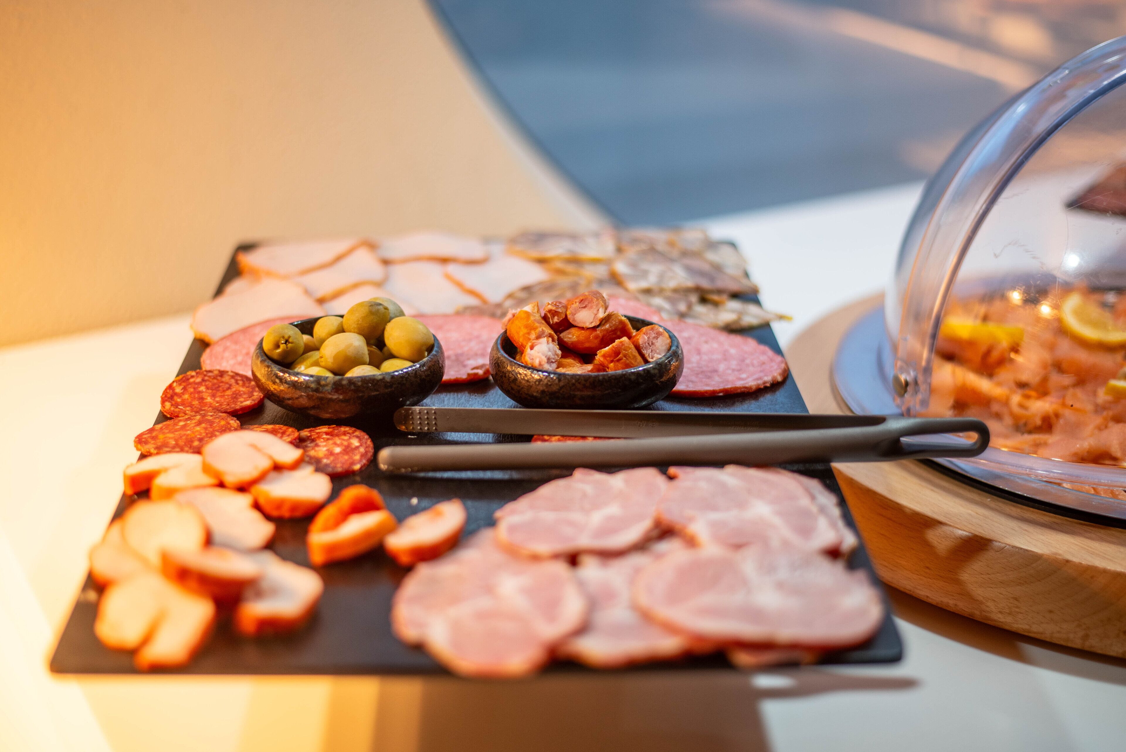 A charcuterie board with various meats and olives.