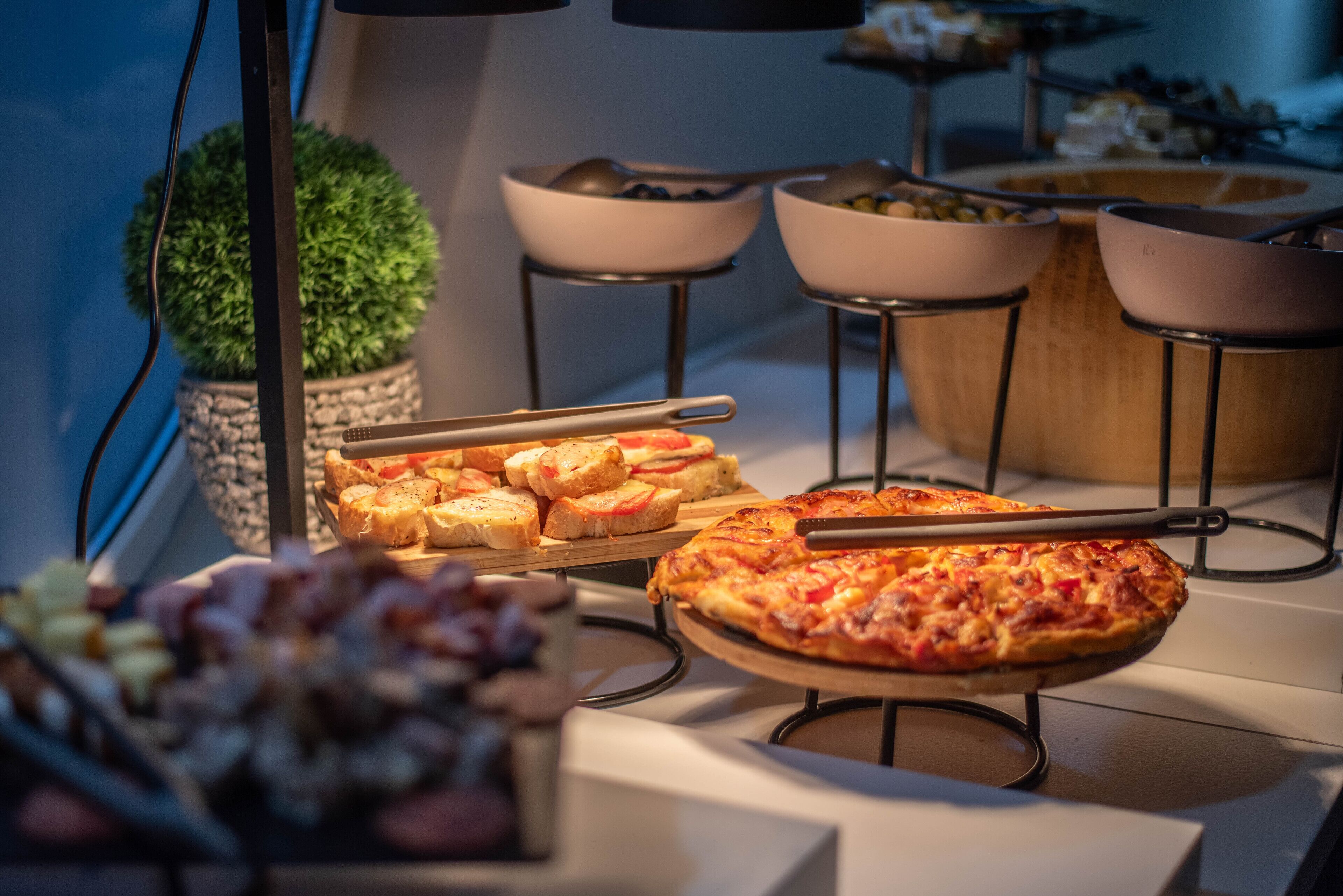 A buffet with various food items including pizza, bread, and salads.