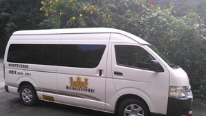 A white van with "Monteverde" and "Historias Lodge" branding, parked in front of dense foliage. - Historias Lodge (Monteverde)