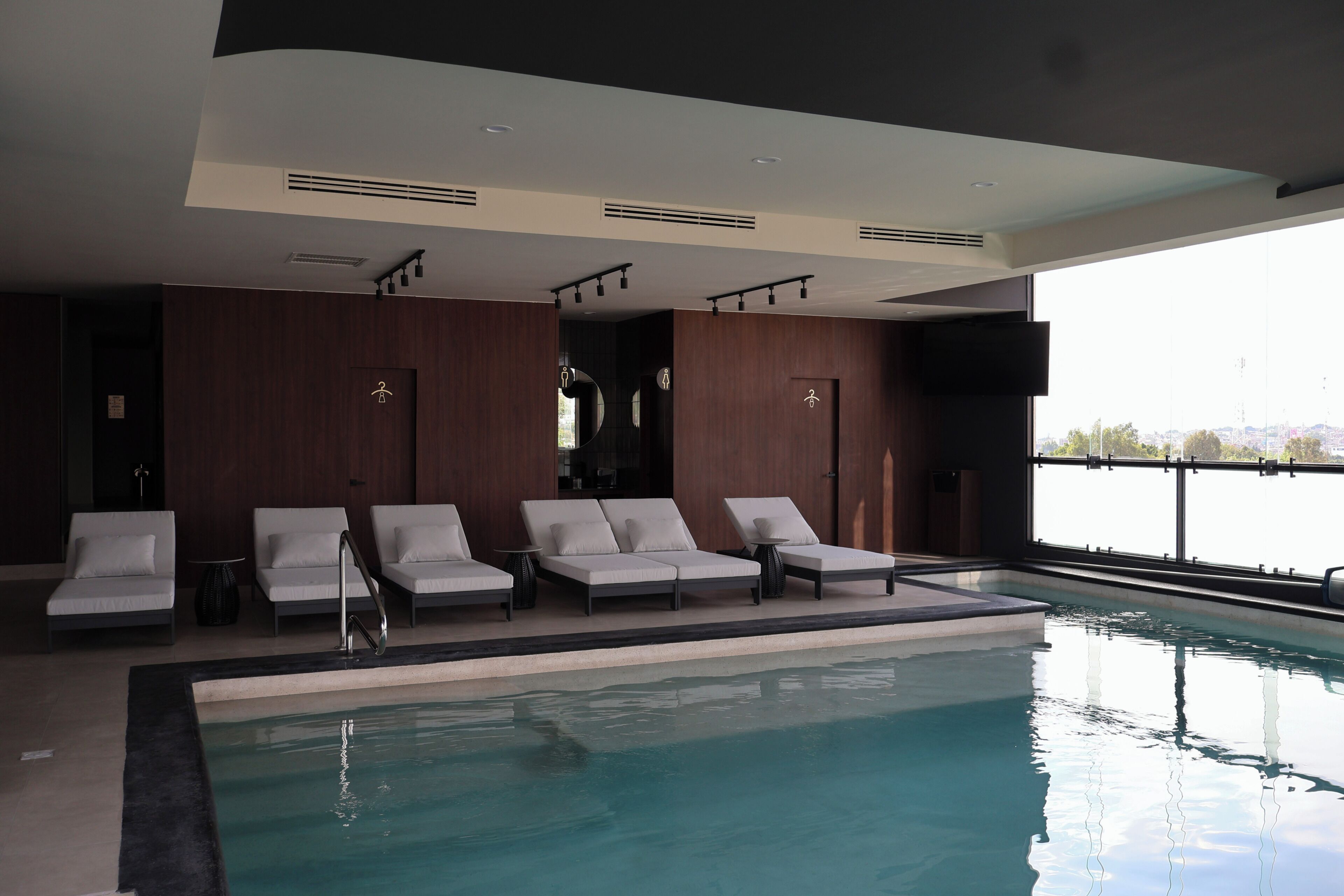 Una piscina con sillas de descanso y vistas a la ciudad.