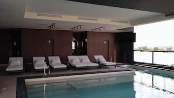 Una piscina con sillas de descanso y vistas a la ciudad.