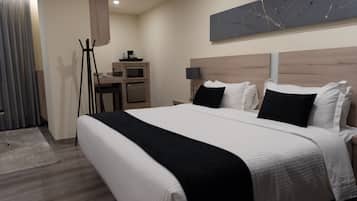 Een moderne hotelkamer met een groot bed, een bureau met een computer, een flatscreen televisie en een kleine kitchenette.