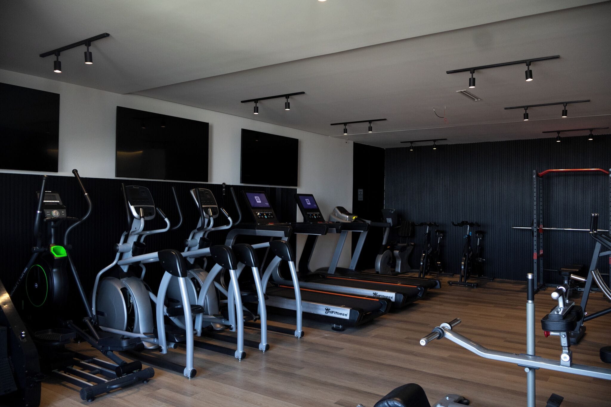 Un gimnasio con cintas de correr, elípticas y equipo de pesas.
