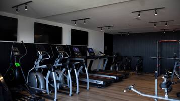 Un gimnasio con cintas de correr, elípticas y equipo de pesas.
