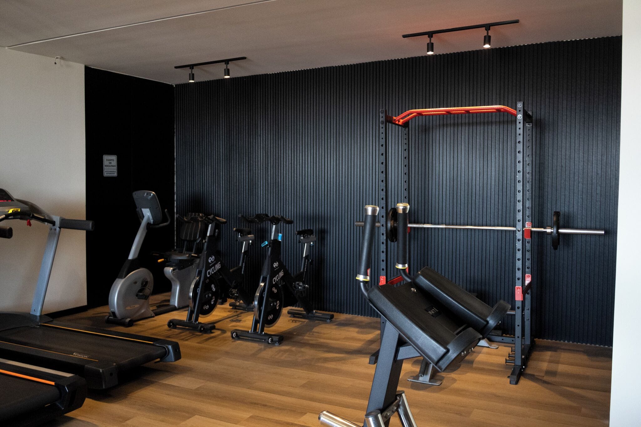 Un gimnasio con equipo cardiovascular, máquinas de pesas y una banca.
