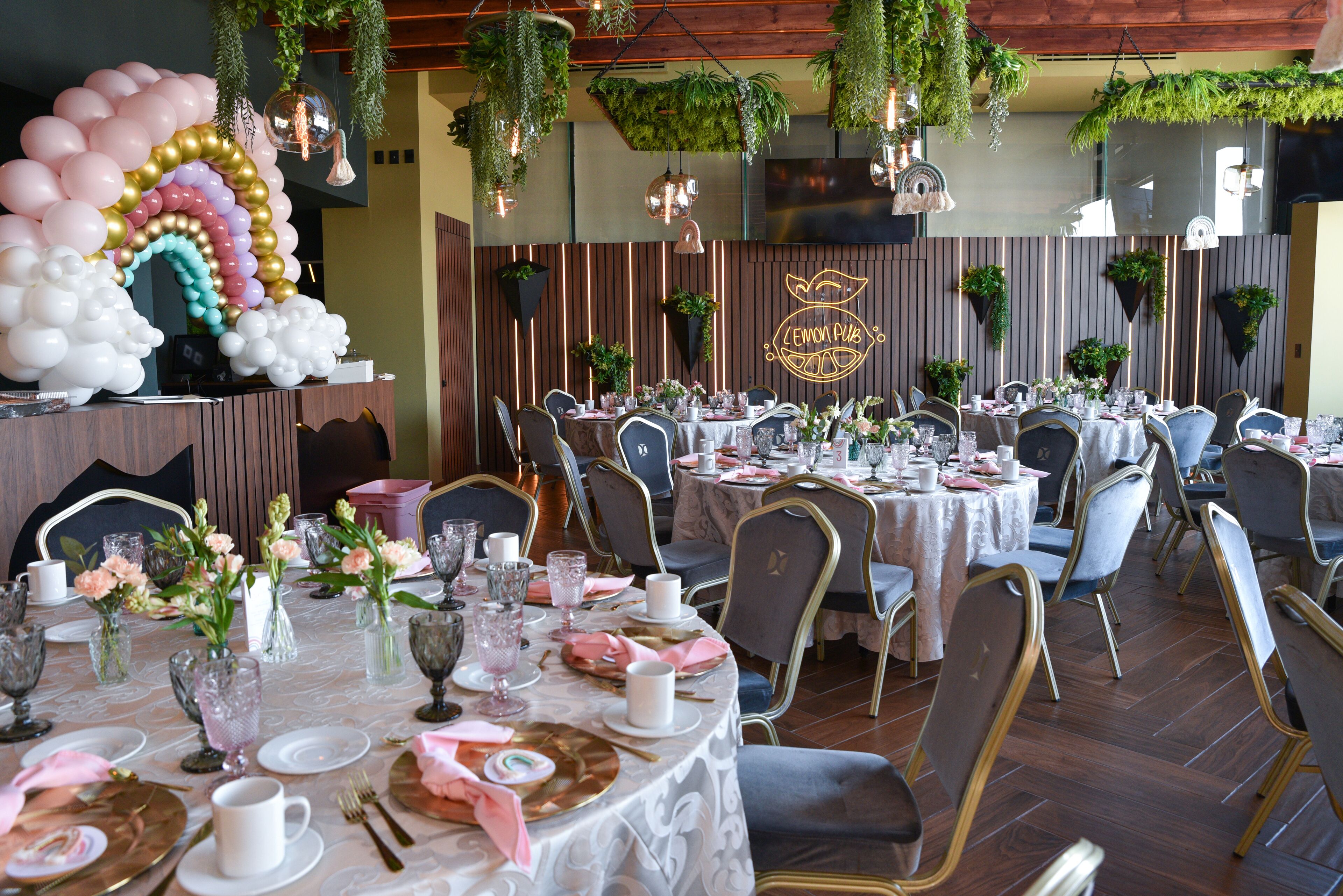 Un restaurante con mesas redondas, sillas y plantas colgantes.