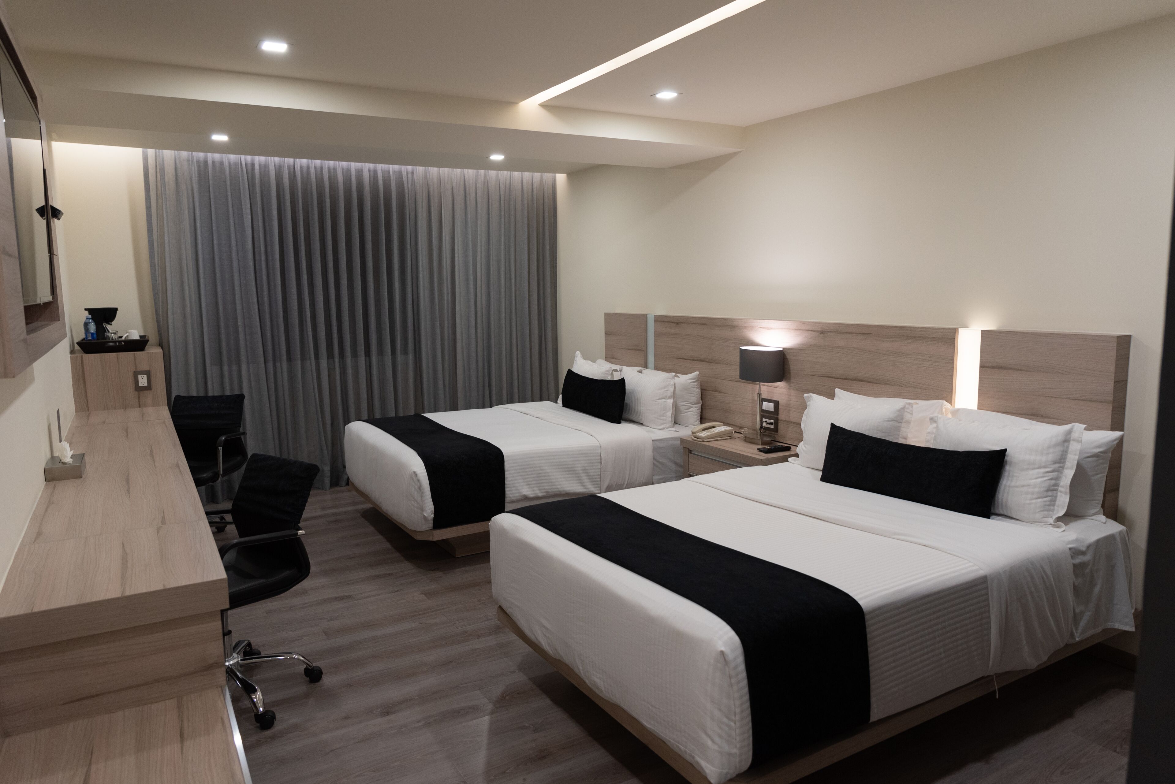 Habitación de hotel con dos camas, un escritorio y una silla.