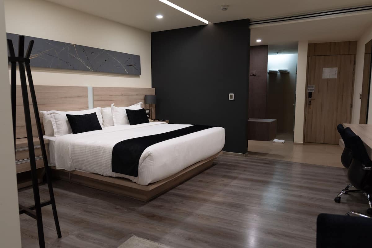 A modern hotel room with a large bed, a desk, and a chair.