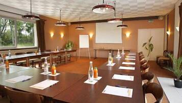 A conference room with a long table, multiple chairs, a projector screen, and a whiteboard.