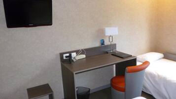 A hotel room with a desk, a chair, a TV, a lamp, and two beds.