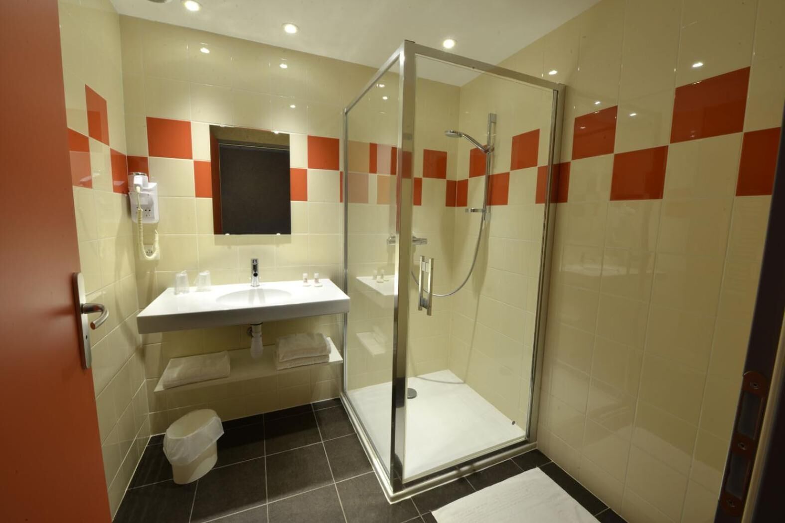 Une salle de bain moderne avec une douche à parois de verre, un lavabo blanc et des toilettes.