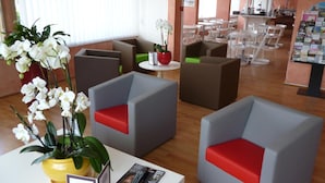 A modern lounge area with seating and a magazine rack. - Hôtel Val Vert (Creancey)