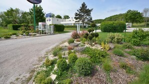 A hotel entrance with a sign, a building, and landscaped gardens. - Hôtel Val Vert (Creancey)