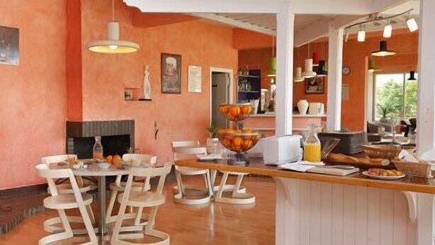 A dining area with a round table, chairs, and a bar counter. - Hôtel Val Vert (Creancey)