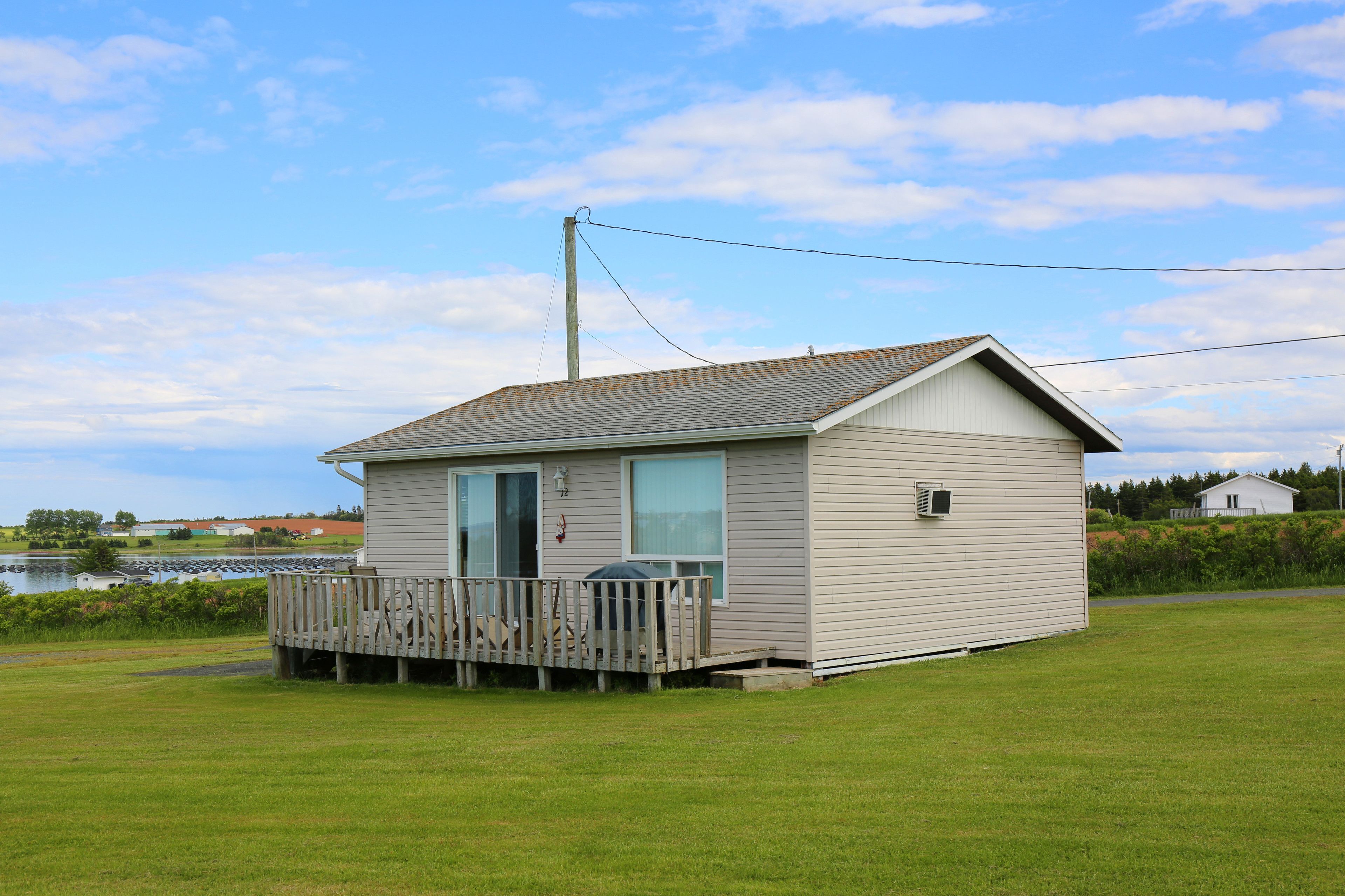 A small, single-story cabin with a wooden deck, a large window, and a door.