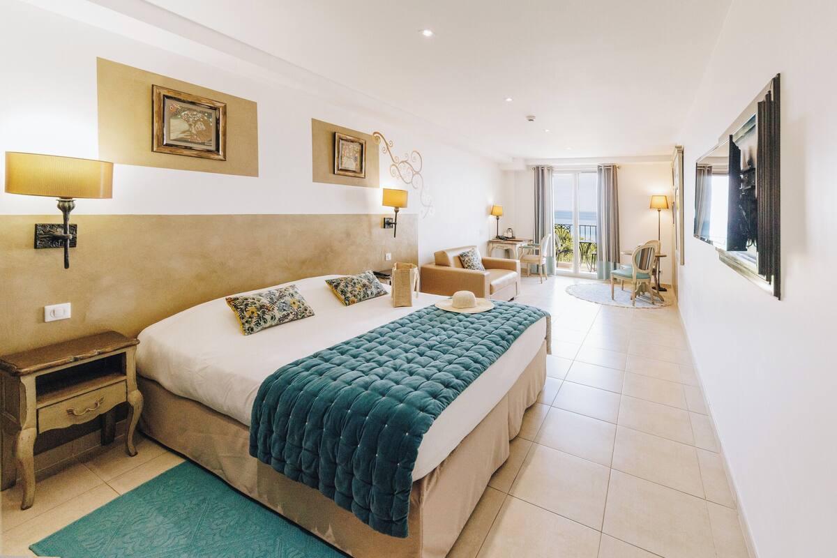 A hotel room with a large bed, bedside tables, a desk, and a view of the outdoors.