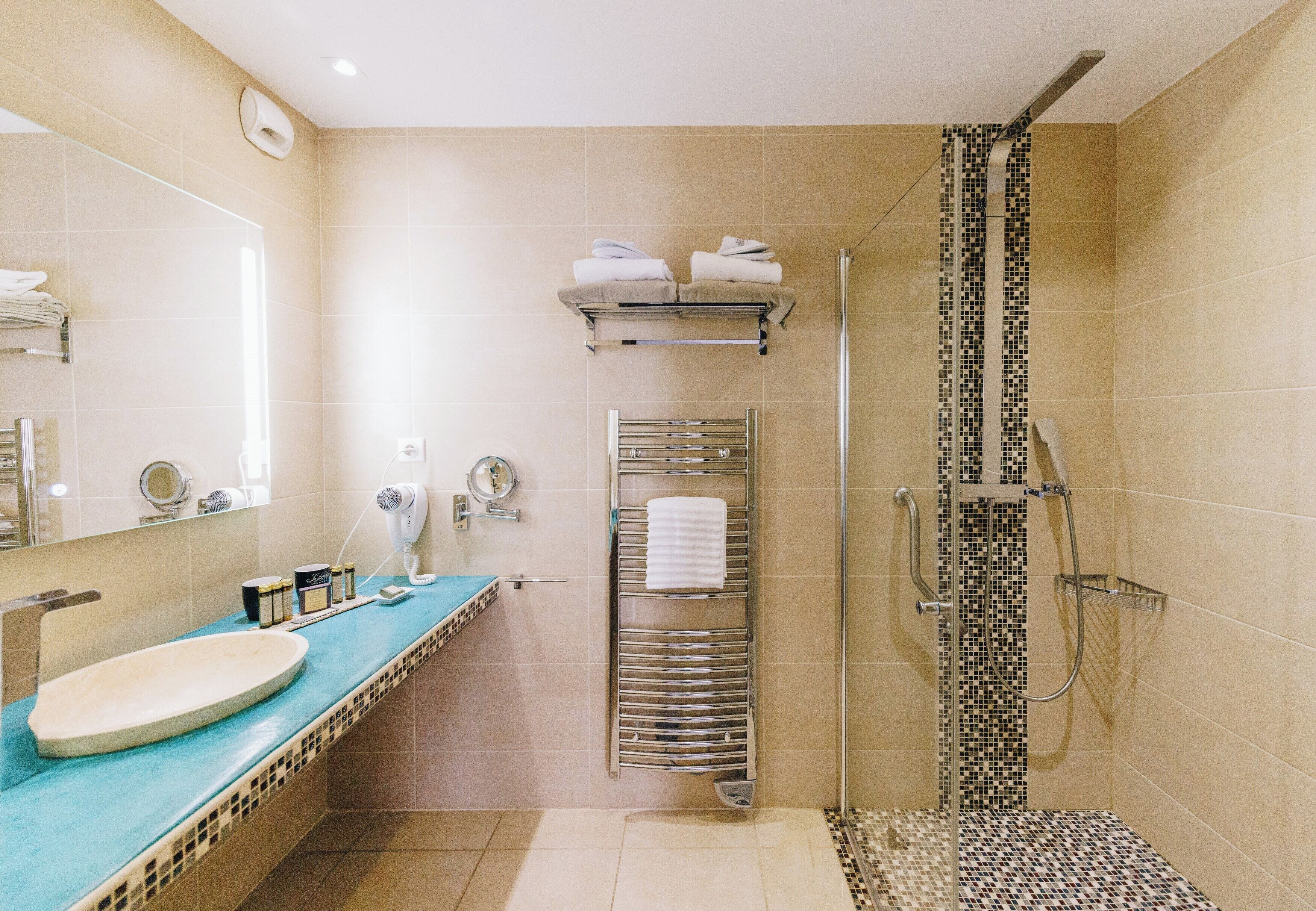 Un baño moderno con lavamanos, espejo, toallero y ducha.