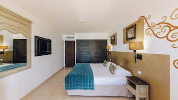 A bedroom with a bed, bedside table, wall-mounted lamp, and a large mirror.