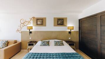 Una habitación de hotel con una cama grande, dos mesitas de noche con lámparas, un sofá y un armario.