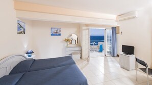 A hotel room with a bed, a desk, a chair, a TV, and a balcony with a view of the sea. - Creta Hotel (Agios Nikolaos)
