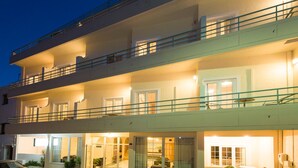 A multi-story hotel with a ground floor entrance, balconies on the upper floors, and a parking area in front. - Creta Hotel (Agios Nikolaos)