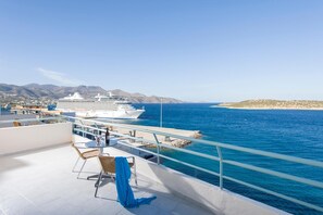 A cruise ship docked at a port with a clear blue sea and mountains in the background. - Creta Hotel (Agios Nikolaos)