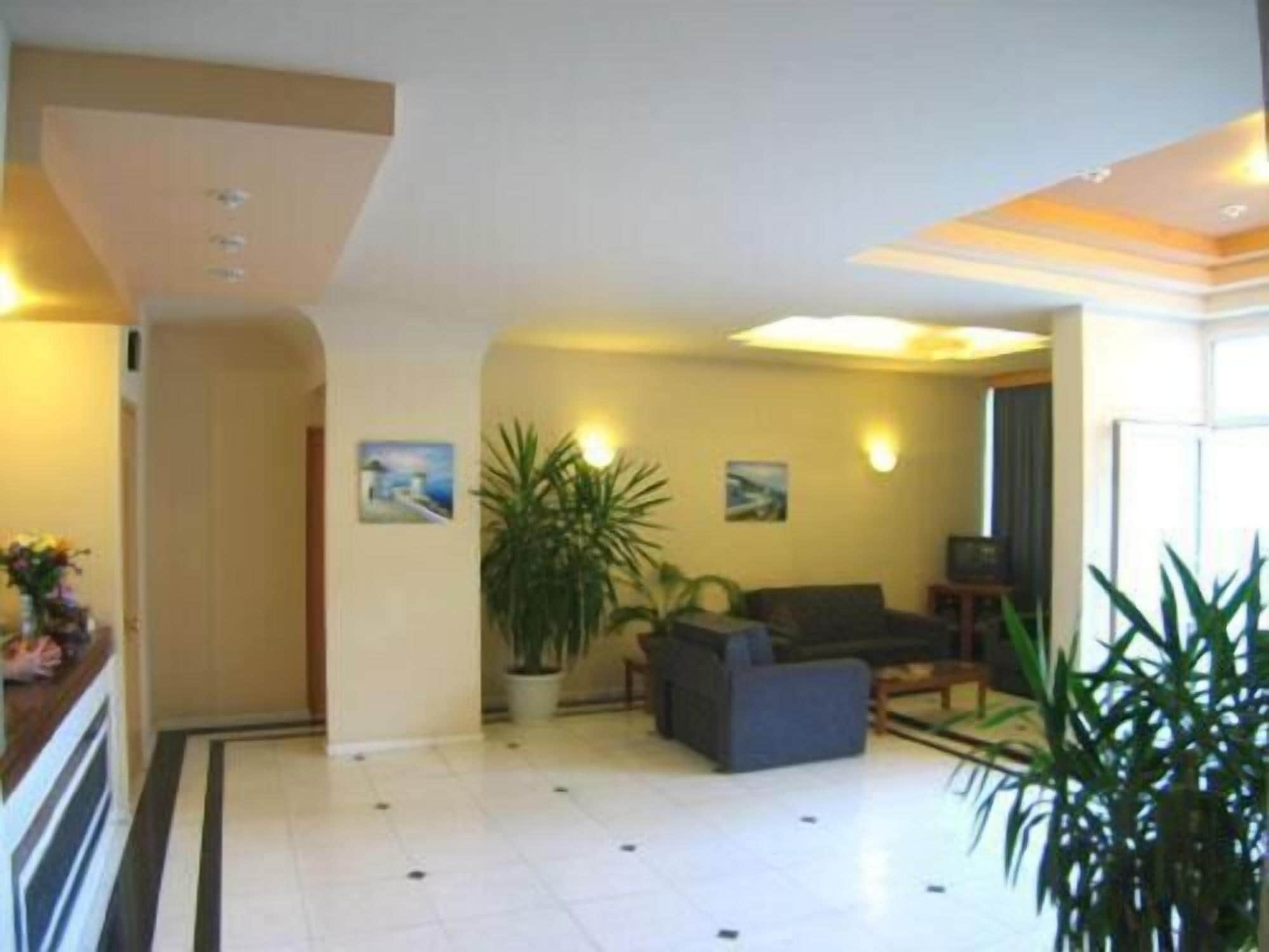 Eine Hotelhalle mit gefliestem Boden, einer Couch, einem Blumentopf und Wandbildern.