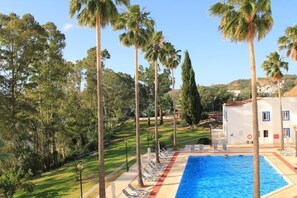 A pool area with lounge chairs and palm trees.