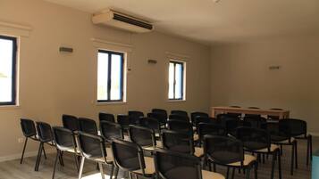 A conference room with rows of chairs, a table, and large windows.