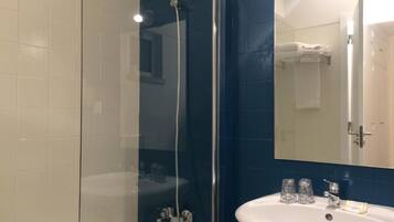 Un baño con ducha de vidrio, lavamanos blanco y espejo.