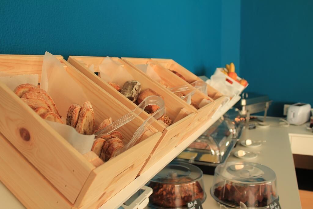 Um buffet de café da manhã com diversos pães e doces, dispostos em recipientes de madeira.
