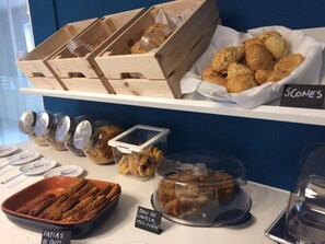 A buffet with various baked goods, including scones and pastries, displayed on shelves.