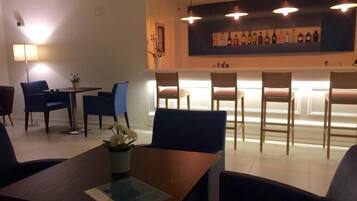 Un comedor con una barra al fondo. Hay varias sillas y una mesa con una planta encima.
