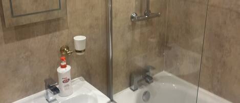 A bathroom with a bathtub, a shower with a glass door, a sink, and a toilet.