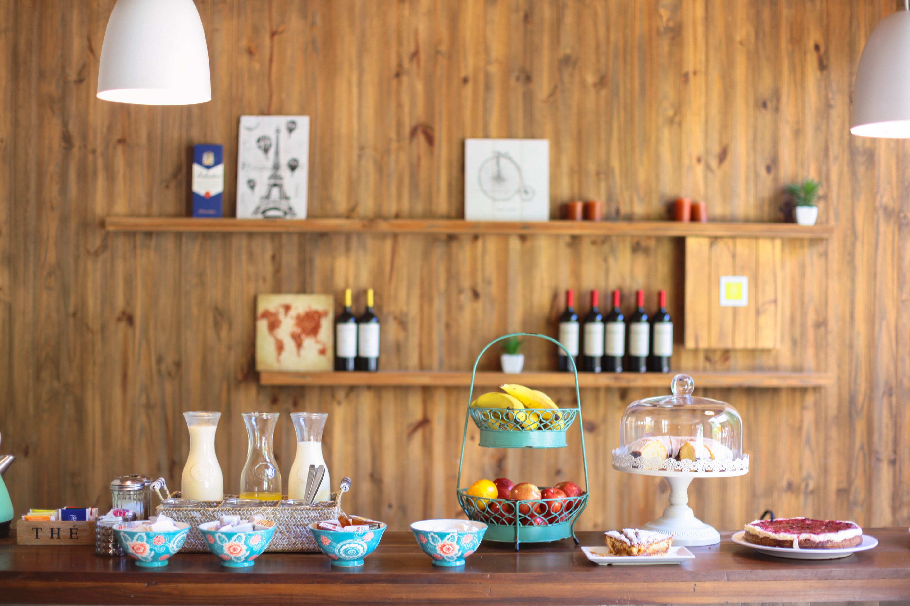 Una pared de madera con estantes que sostienen botellas de vino, una cesta de frutas y adornos.