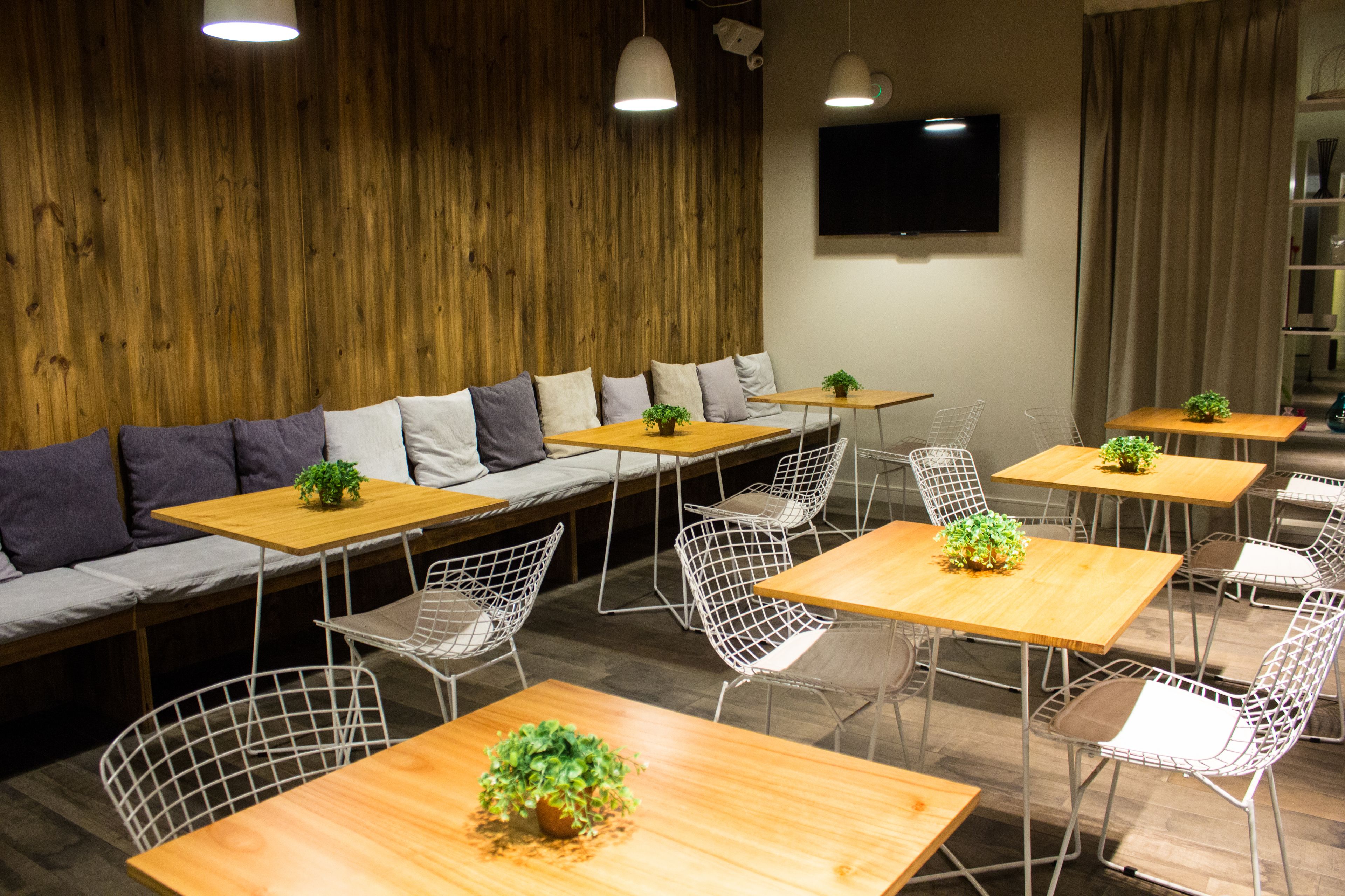 Un café moderno con paredes de madera, un sofá con cojines y mesas con sillas.