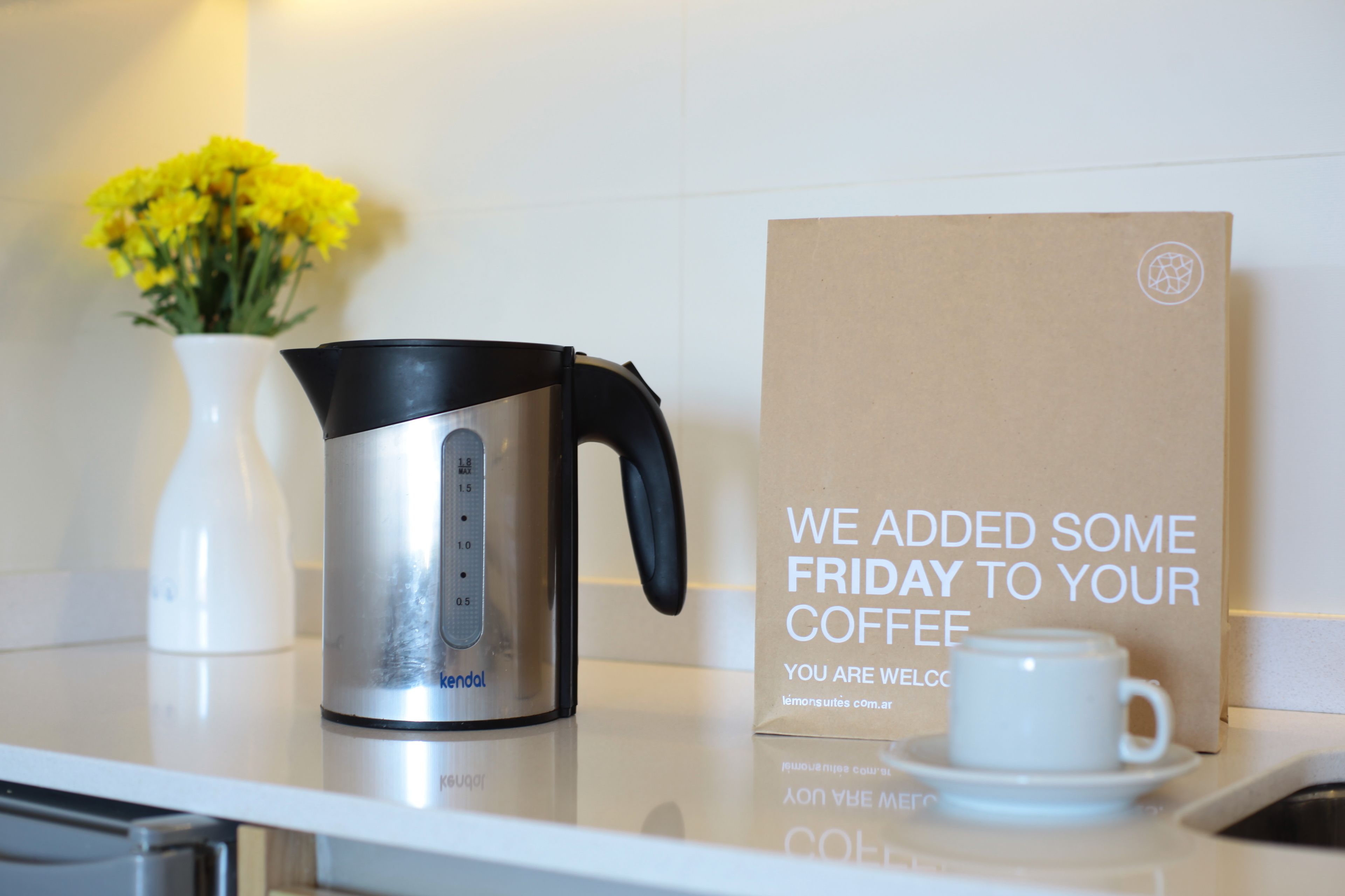 A coffee maker, a white cup, and a card on a counter.