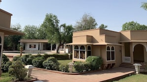 Un patio con un edificio que tiene ventanas de arco y un corredor cubierto.