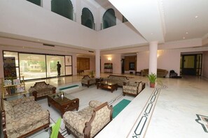 A spacious lobby with multiple seating areas, a reception desk, and a large window. - Heritage Resort (Bikaner)