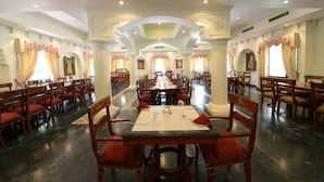 Un comedor amplio con varias mesas y sillas, techos altos y arcos decorativos.