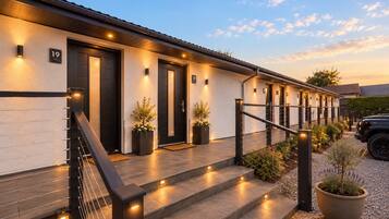 Un hotel con fachada moderna, puertas numeradas y una entrada bien iluminada con escalones y barandilla.