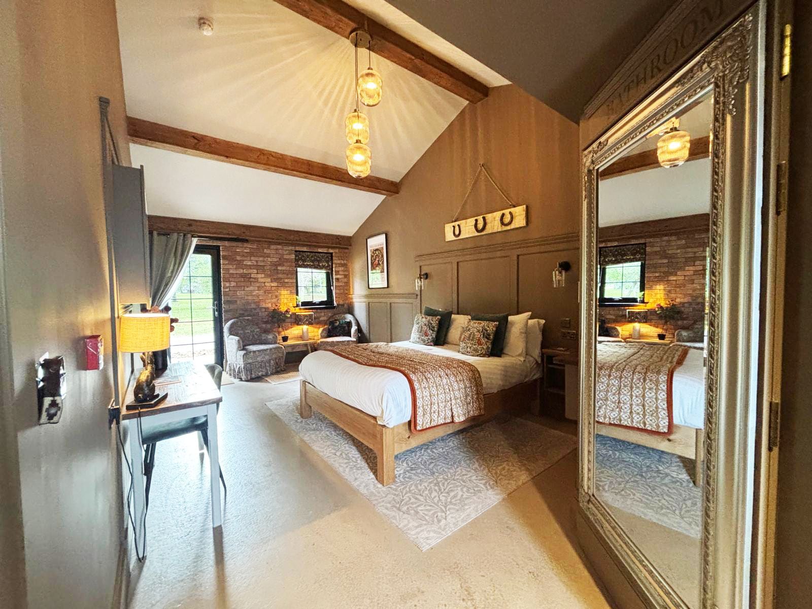 Un dormitorio con una cama grande, un escritorio y un espejo.