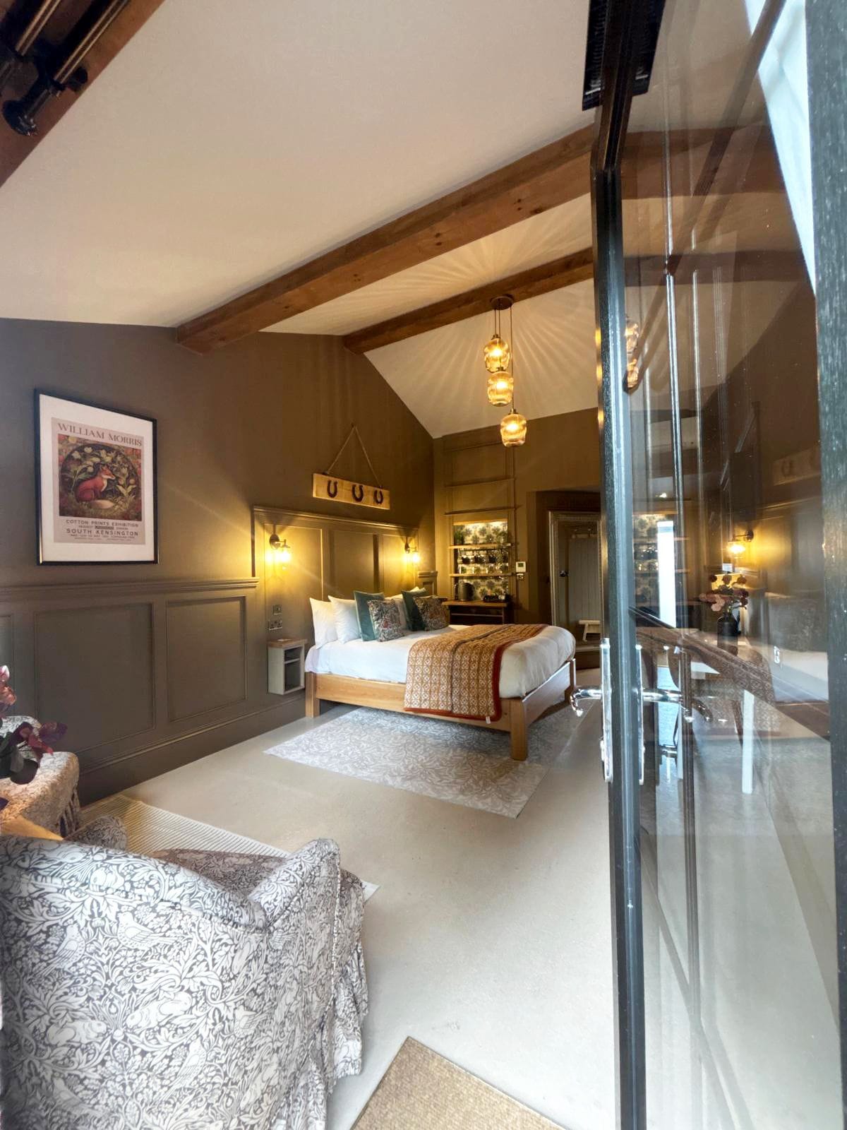 A bedroom with a bed, bedside tables, a hanging light fixture, and a framed picture on the wall.