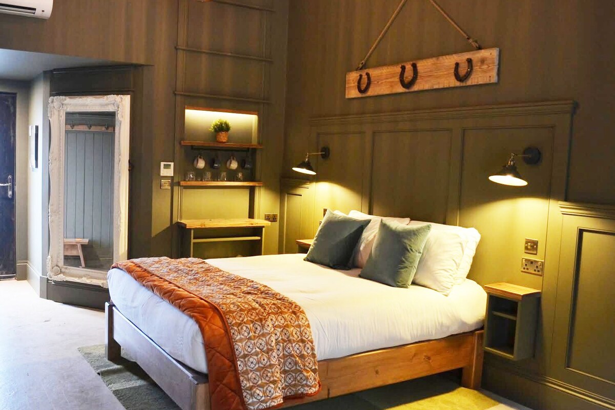 Un dormitorio con cama, mesitas de noche, una estantería con objetos decorativos y un cartel en la pared.