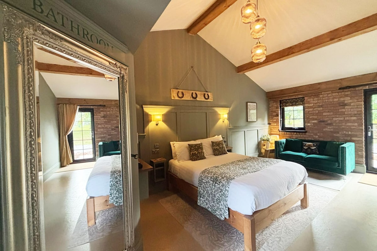Un dormitorio con una cama grande, un espejo, un cartel sobre la cama, un sofá verde y una pared de ladrillo.