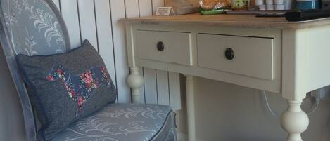 A chair with a floral cushion, a table with a lamp, and a basket labeled "Waste Bin".