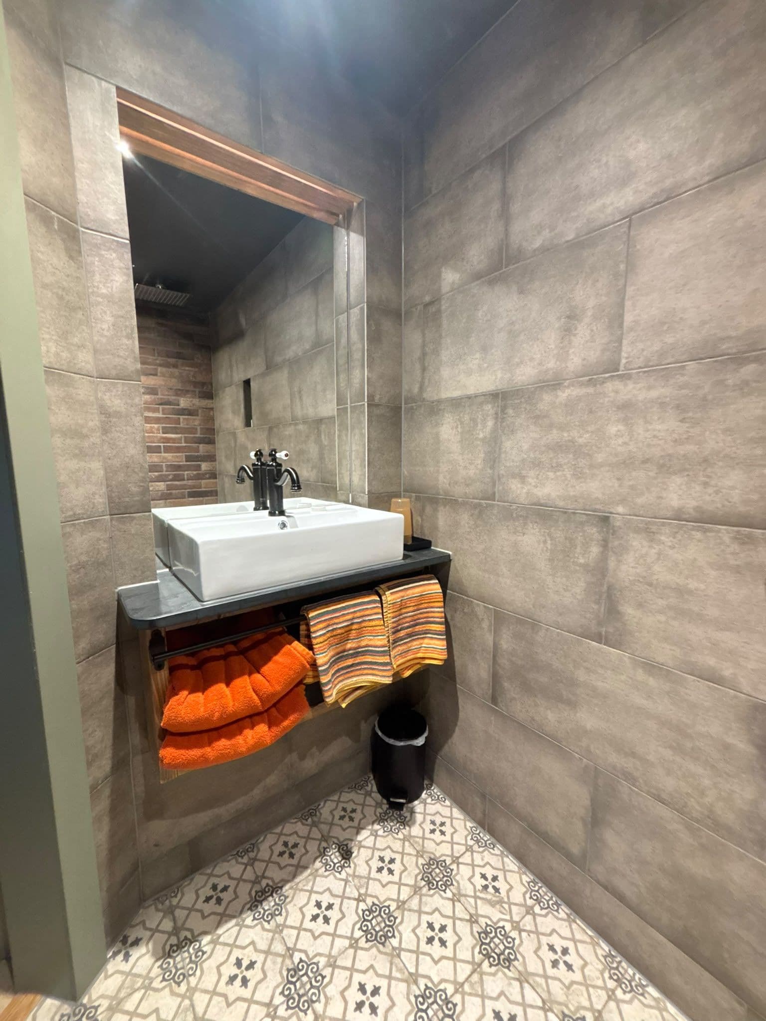 A bathroom with a white sink, striped towels, and patterned floor tiles.